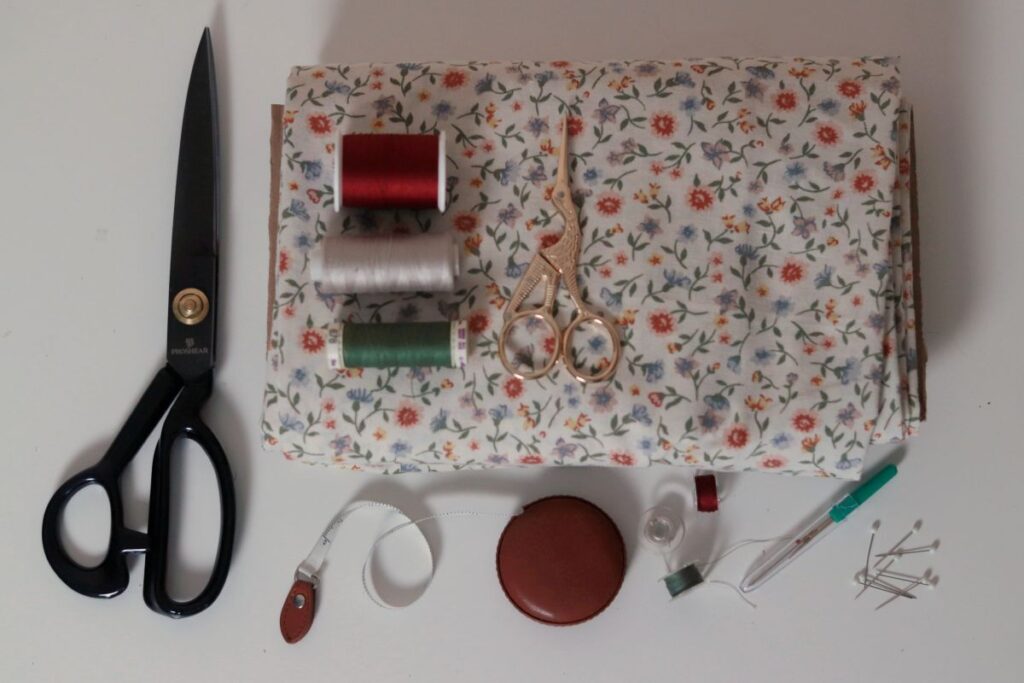 sewing supplies and notions lying on and around floral fabric