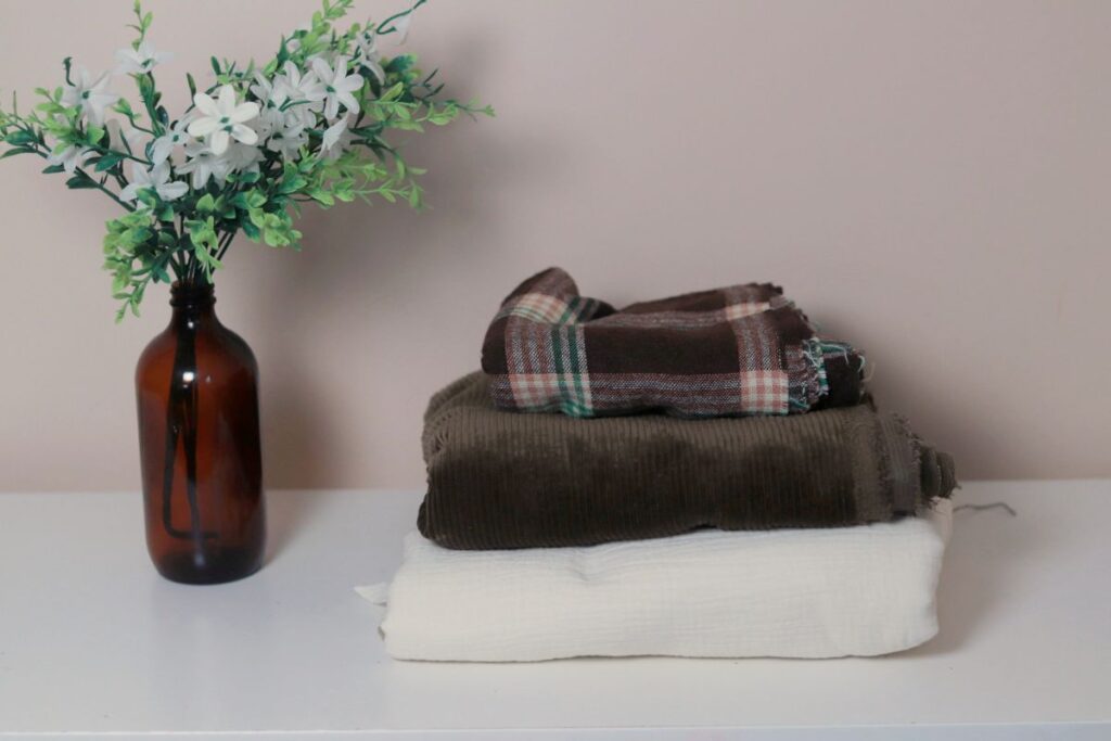 stack of fabrics sitting next to small bouquet of white flowers