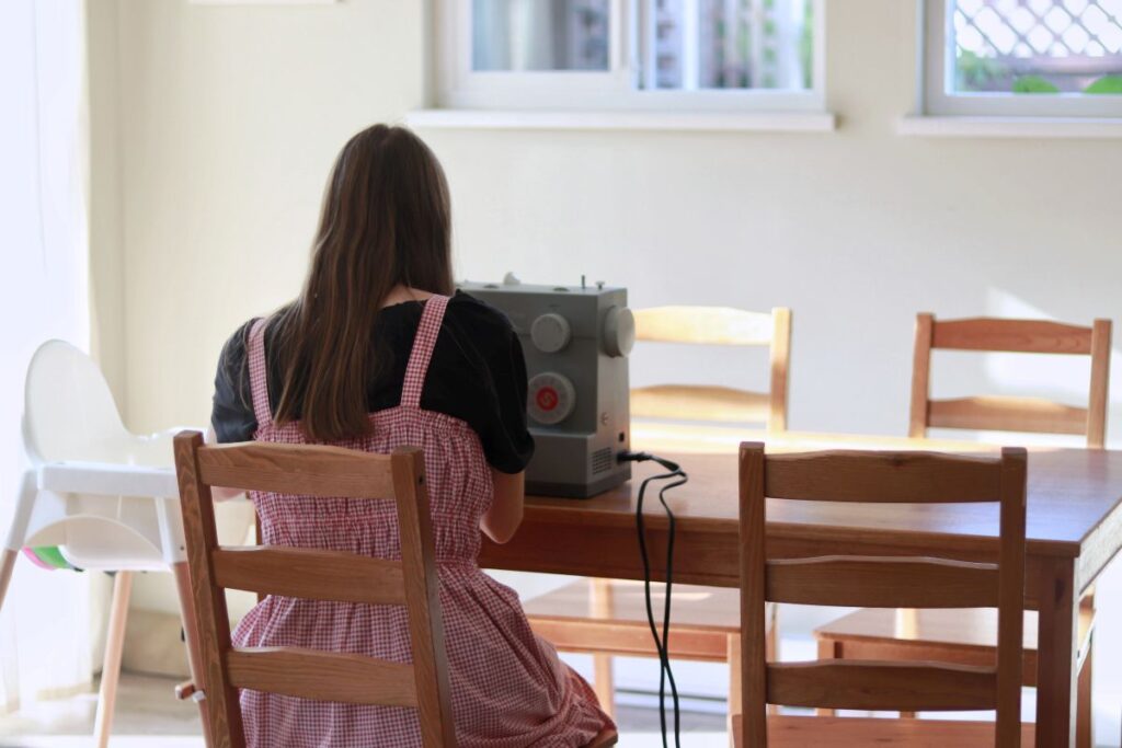 woman sitting at table in front of sewing machine 