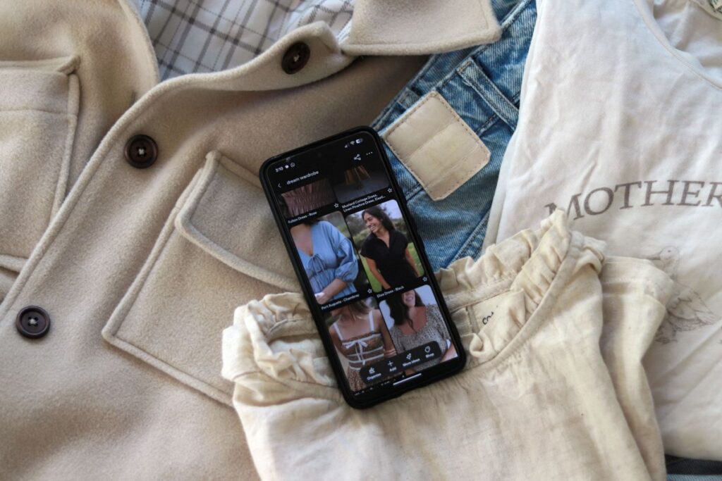 phone laying on pile of clothes displaying Pinterest clothing board
