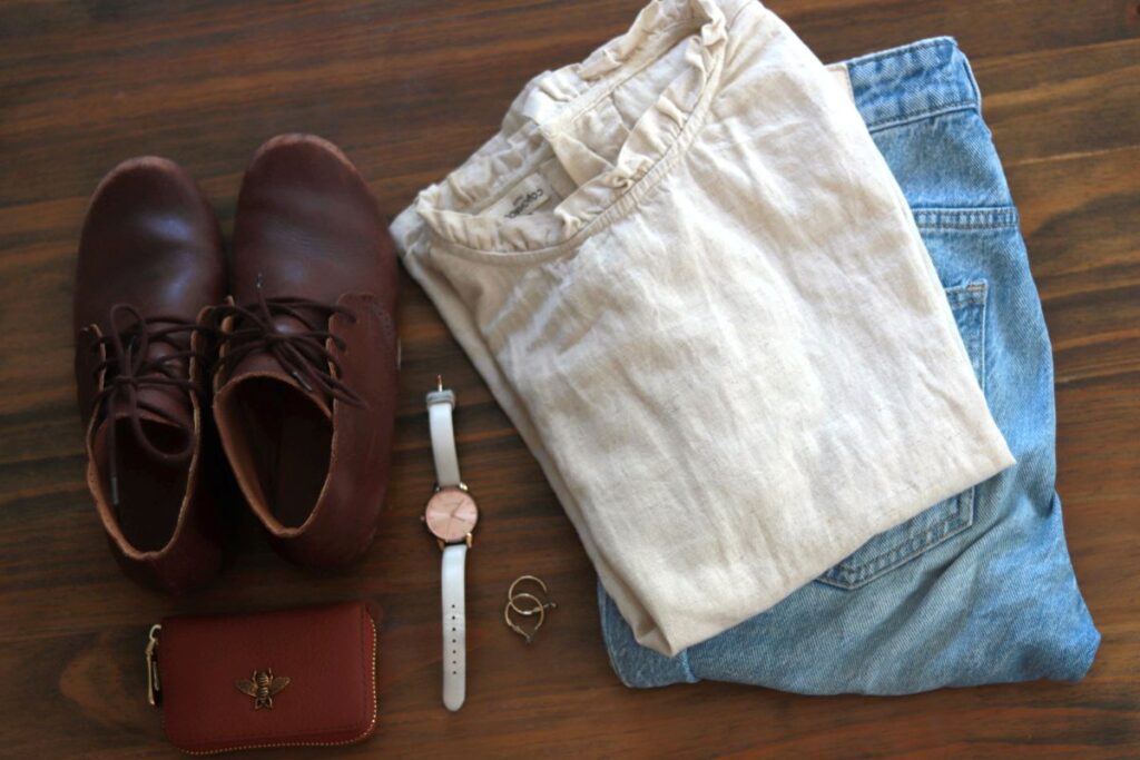 shirt, pants, shoes, watch, earrings, and wallet arranged on table
