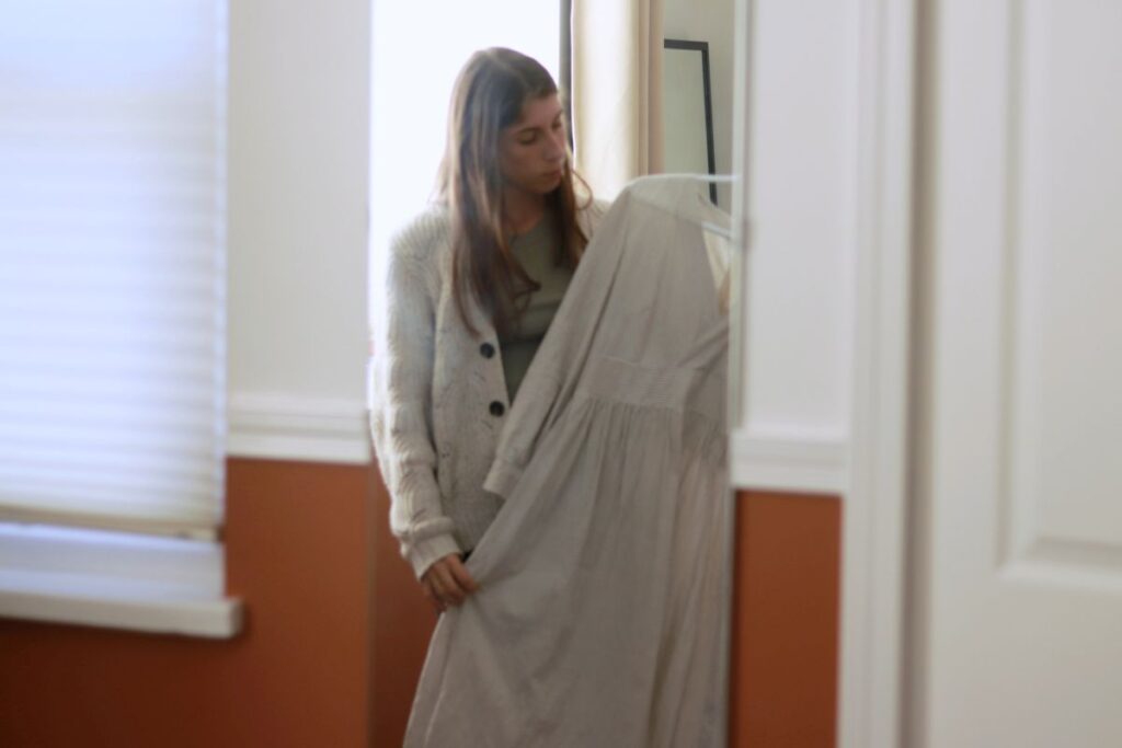 reflection of woman in mirror holding up a dress