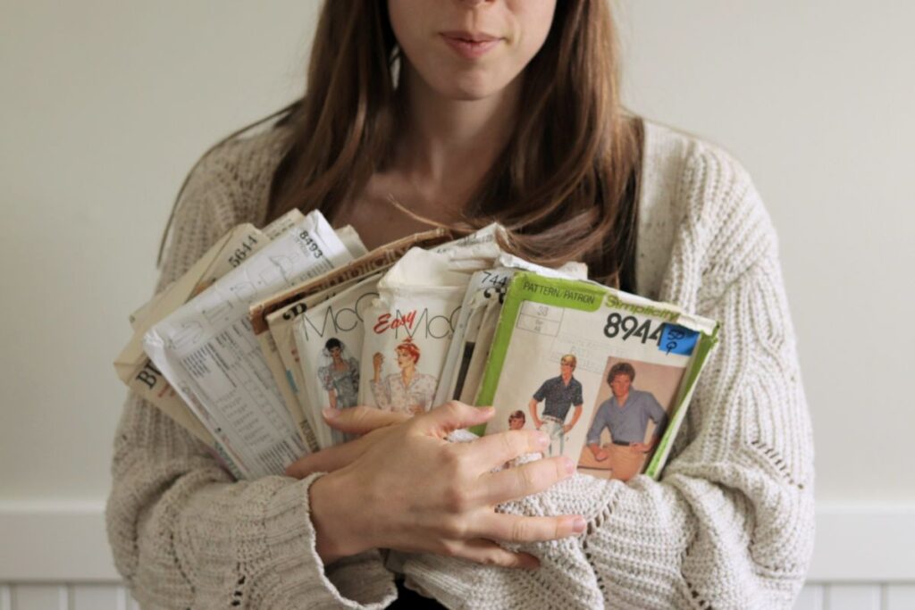 woman holding armful of vintage sewing patterns