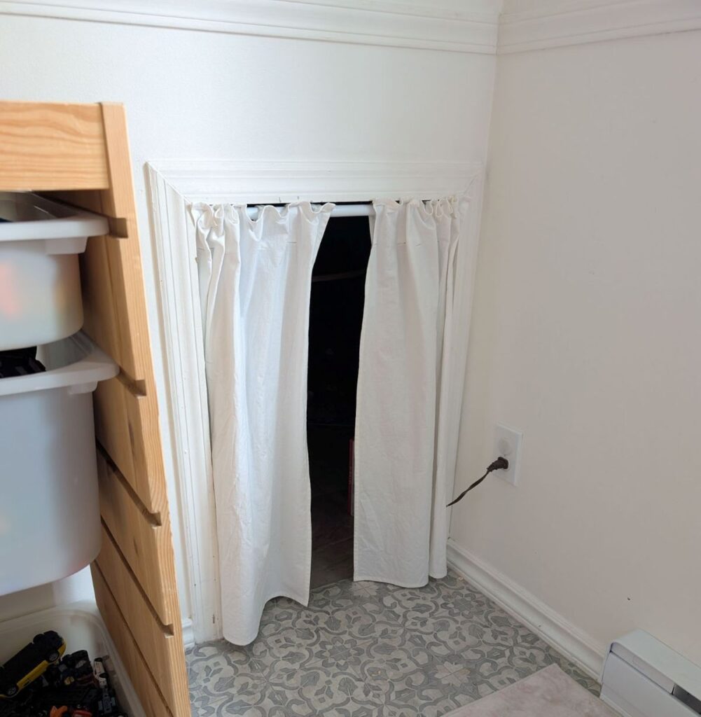 side angle of small room under stairs covered by diy curtains
