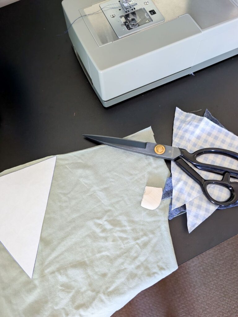 fabric marked with tailors chalk laying next to sewing machine with fabric scissors on top